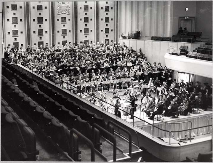 New Free Trade Hall, 1951, White, Daily Herald Archive, ©National Media Museum With the huge platform packed to its full capacity, Sir John Barbirolli rehearses the augmented Halle Orchestra and chorus in preparation for the Royal opening of the rebuilt Free Trade Hall the following day. This is the first time the Halle have played together in full strength at this famous hall since the blitz.